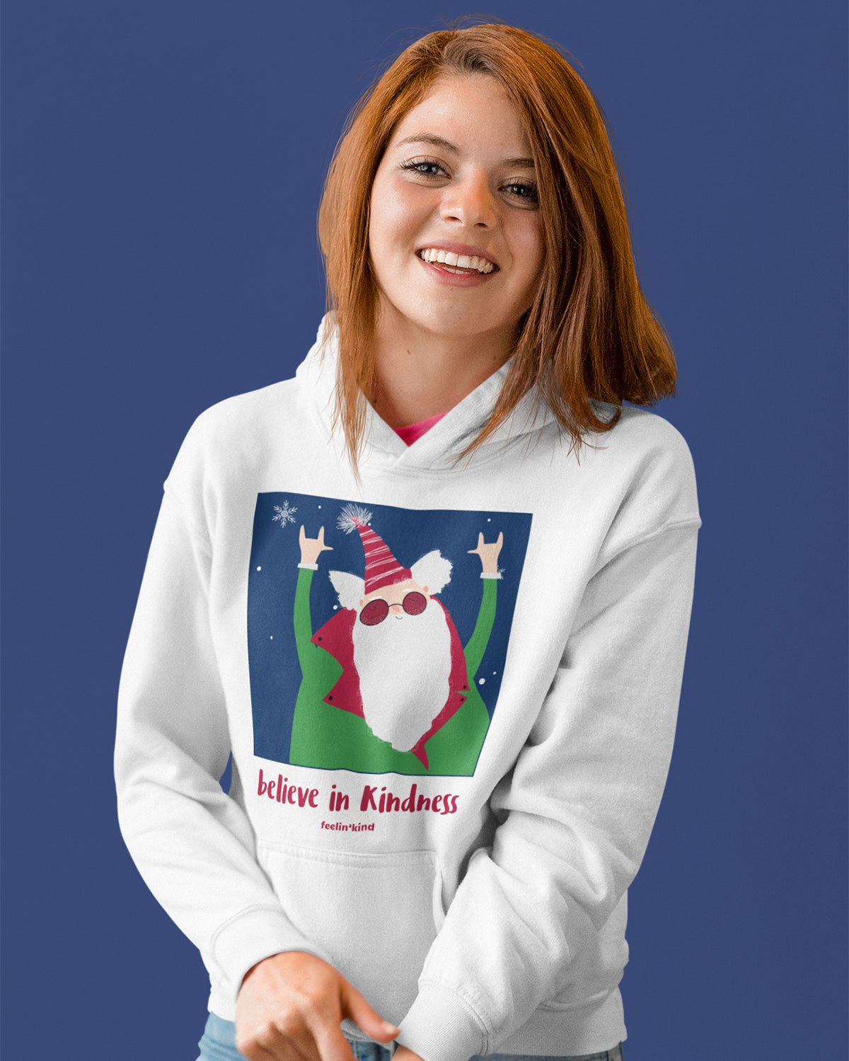 Young woman wearing a Believe in Kindness hoodie featuring a cool Santa design inspired by the spirit of goodwill, perfect for the holidays.