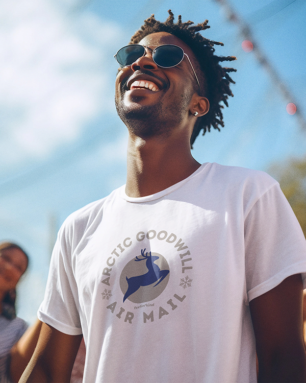 Man wearing Arctic Goodwill Air Mail unisex t-shirt of a majestic deer leaping embodies strength and kindness in a wilderness-inspired design.